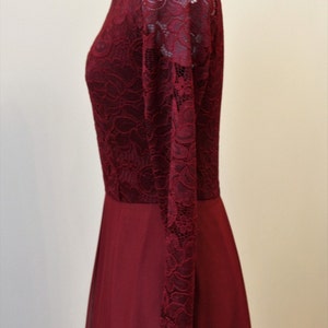 May include: A burgundy maxi dress with long sleeves made of lace. The dress has a fitted bodice and a flowing skirt.