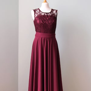 May include: A long, burgundy dress with a lace bodice and a simple, flowing skirt. The dress is sleeveless and has a fitted waist.