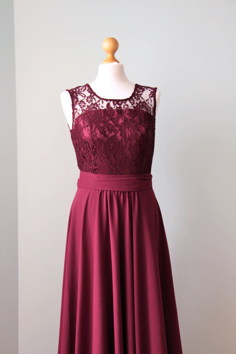 May include: A burgundy sleeveless maxi dress with a lace bodice and a satin sash.