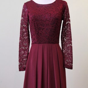 May include: A long-sleeved burgundy dress with a lace bodice and a pleated skirt.