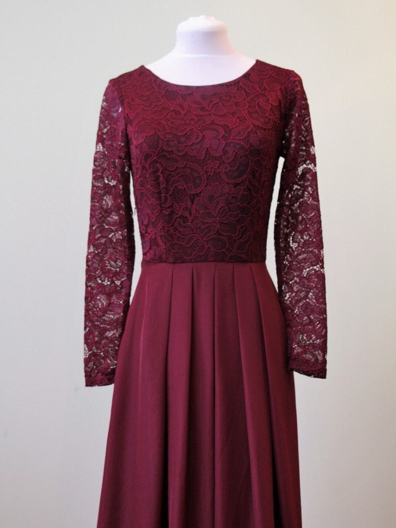 May include: A long-sleeved burgundy dress with a lace bodice and a pleated skirt.