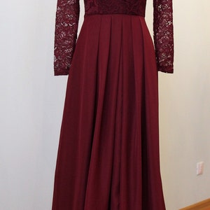 May include: A long, burgundy dress with a lace bodice and long sleeves. The skirt is pleated and flows to the floor.