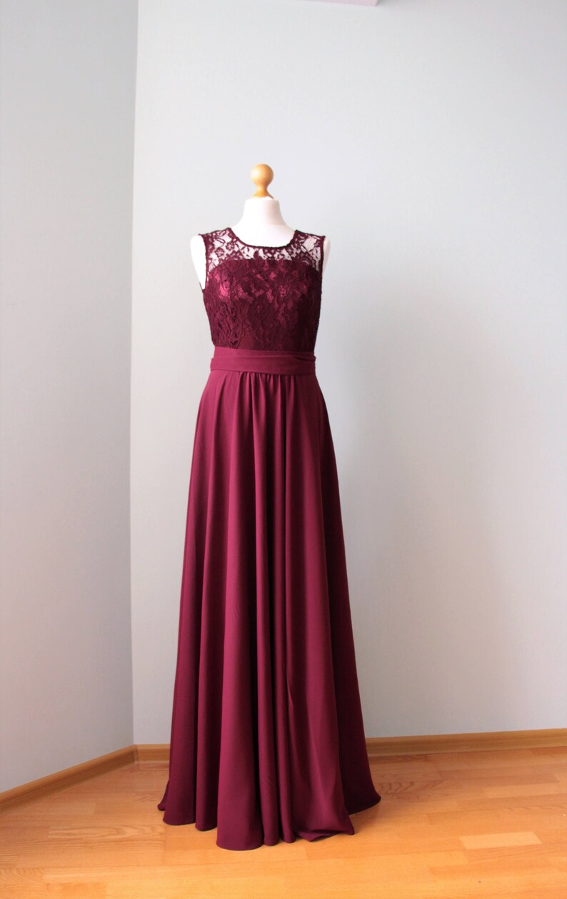 May include: A long, burgundy bridesmaid dress with a lace bodice and a simple, flowing skirt.