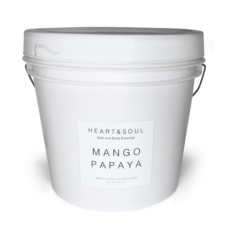 May include: A white plastic bucket filled with mango papaya sugar scrub. The label reads "HEART&SOUL Bath and Body Essential MANGO PAPAYA MANGO PAPAYA SUGAR SCRUB NET WT 16 OZ (453.6 G)"