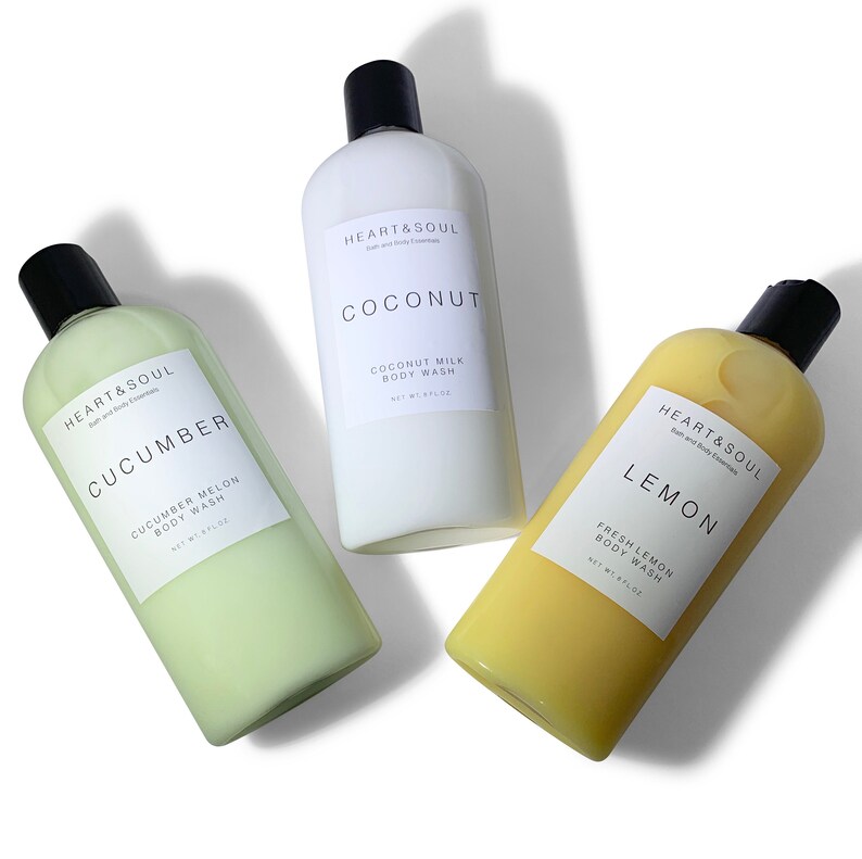May include: Three clear plastic bottles of body wash with white labels. The bottles are labeled "HEART & SOUL" and contain the scents "COCONUT", "CUCUMBER", and "LEMON".