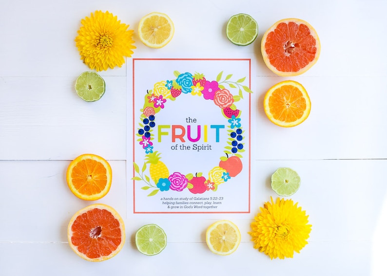 May include: A colorful printable poster with a wreath of flowers and the text "the FRUIT of the Spirit". The poster is surrounded by lemons, limes, and grapefruits on a white wooden background.