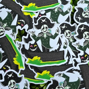 May include: A collection of die-cut stickers featuring a character dressed as a pirate with a black hat, a white skull and heart emblem, and a green coat. The character has a skeletal appearance, a parrot on the shoulder, and a black cat nearby.