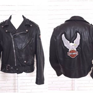 May include: Black leather motorcycle jacket with a Harley Davidson eagle patch on the back. The jacket has a zipper closure and a belt at the waist.
