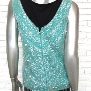 May include: A sleeveless turquoise sequined top with a zipper down the back and a fringe trim.