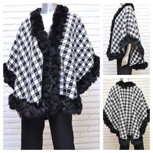 May include: Black and white checkered poncho with a black faux fur trim. The poncho has a loose fit and is made of a soft, warm fabric.