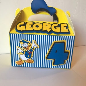 Pode incluir: Uma caixa de lembrancinhas de festa amarela e azul com um personagem do Pato Donald, o nome "GEORGE" e o n&uacute;mero "4" impressos nela.