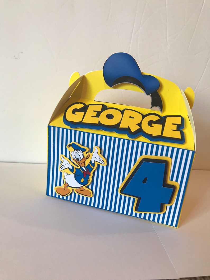 Pode incluir: Uma caixa de lembrancinhas de festa amarela e azul com um personagem do Pato Donald, o nome "GEORGE" e o n&uacute;mero "4" impressos nela.