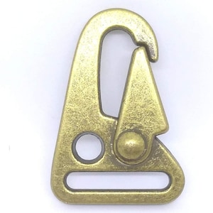 May include: A gold-toned metal trigger snap hook with a D-ring. The hook has a textured finish and a small hole on the side.