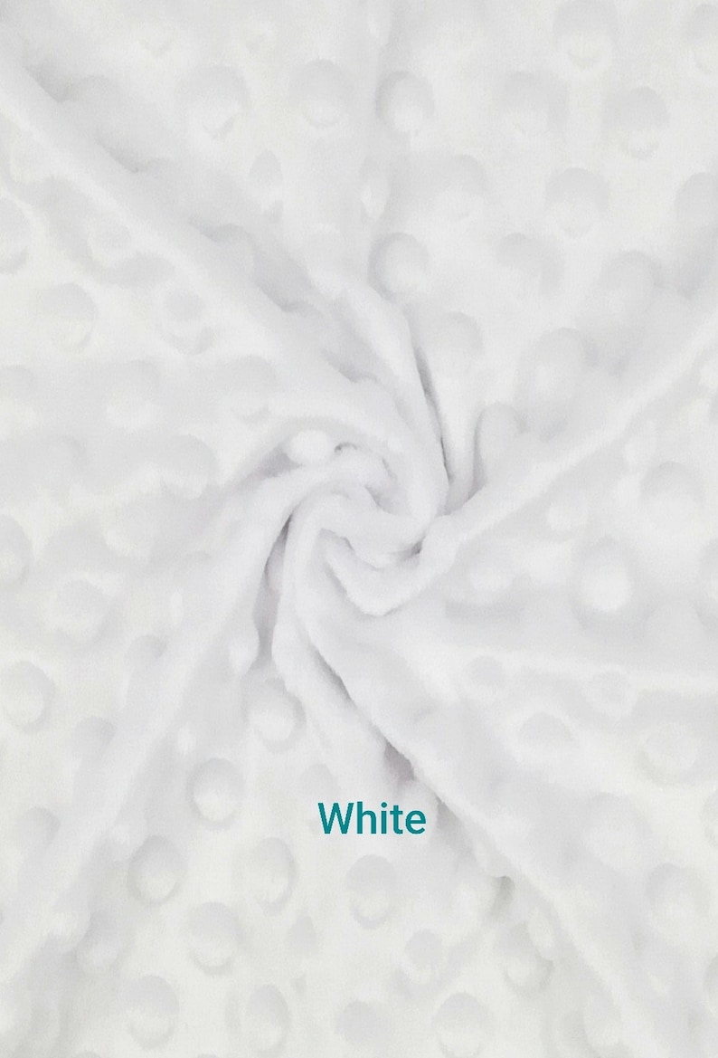 May include: White fabric with a textured, dimpled surface. The fabric is soft and plush, with a swirling pattern. The word "White" is printed in the image. This fabric is suitable for blankets, baby items, and other craft projects.