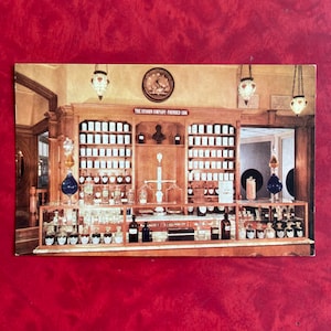 May include: A vintage apothecary shop interior with wooden shelves filled with glass bottles and jars. The shop has a sign that reads "The Upjohn Company - Founded 1886".