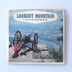 May include: A View-Master reel box featuring a vintage image of Lookout Mountain, Tennessee. The box shows a cannon on a cliff overlooking a city and river. The text on the box reads "Lookout Mountain Tennessee" and "View-Master 21 stereo pictures".