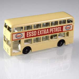 Peut inclure: Un jouet de bus à impériale vintage de couleur crème avec des roues noires. Le bus présente le logo Esso Extra Petrol en rouge et blanc. Un jouet de collection classique.