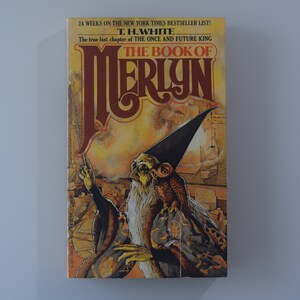 May include: A book cover with a yellow and orange background featuring a wizard with a long white beard and a black pointed hat. The title of the book is "The Book of Merlin" by T.H. White. The text on the cover also states that it is the "true last chapter of The Once and Future King".