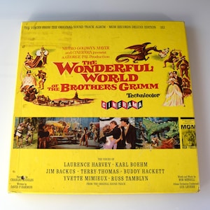 May include: A vintage vinyl record album cover for "The Wonderful World of the Brothers Grimm" in Technicolor. The yellow cover features illustrations of characters and scenes from the film, with the title in large red letters. The album is a Metro-Goldwyn-Mayer and Cinerama production.