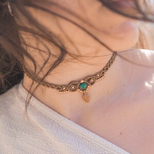 May include: A brown macrame choker necklace with a green gemstone and a gold leaf pendant.
