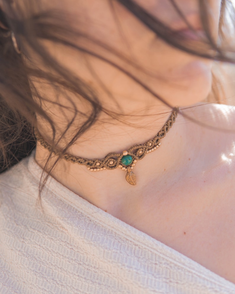 May include: A brown macrame choker necklace with a green gemstone and a gold leaf pendant.