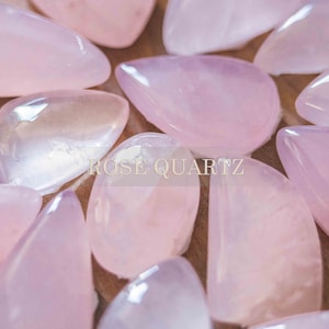 May include: A close-up of a collection of rose quartz stones, each with a unique shape and size. The stones are a pale pink color and have a smooth, polished finish. The text "ROSE QUARTZ" is visible in the center of the image.
