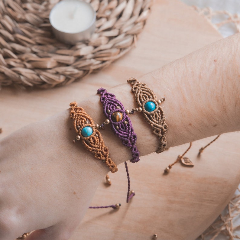 May include: Three macrame bracelets with gemstone beads. The bracelets are brown, purple, and blue with gold accents.