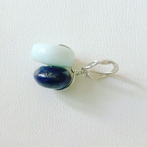 May include: A silver charm with a light blue and dark blue gemstone pendant.