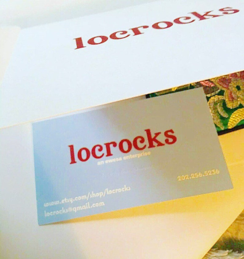May include: A blue business card with the text "locrocks an evessa enterprise" in red. The card also includes the website address "www.etsy.com/shop/locrocks" and the email address "locrocks@gmail.com". The phone number "202.256.5236" is printed in white on the card.