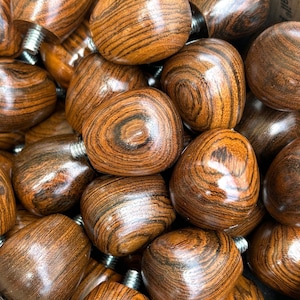 May include: A close-up of a group of wooden knobs with a dark brown and light brown striped pattern. The knobs have a shiny finish and are arranged in a random pattern.