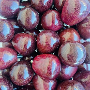 May include: A close-up of a group of dark purple wooden knobs. The knobs are smooth and have a glossy finish.