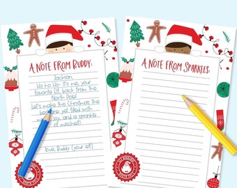 May include: Two Christmas-themed notepads with festive illustrations and text. One notepad has a blue pencil, the other a yellow pencil. The text on the notepads reads "A Note From Buddy" and "A Note From Sparkles."