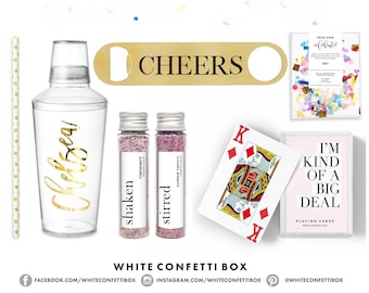 May include: A 21st birthday party kit with a clear plastic cocktail shaker, a gold bottle opener with the word "CHEERS" on it, two small glass bottles with confetti, a deck of playing cards with the text "I'm kind of a big deal", and a small bag of confetti.