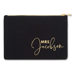 May include: Black zippered pouch with a gold zipper and the text "MRS Jacobsen" in gold script.
