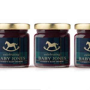 May include: Three small jars of jam with gold lids. Each jar has a label with a rocking horse graphic and the text "celebrating BABY JONES LAUREN'S BABY SHOWER". The labels have a navy and green plaid pattern.