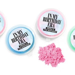 May include: Three clear plastic containers with pink, blue, and green lids. Each container has a white and blue watercolor background with black text that reads "In My Birthday Era" and "Emma's 7th Birthday".