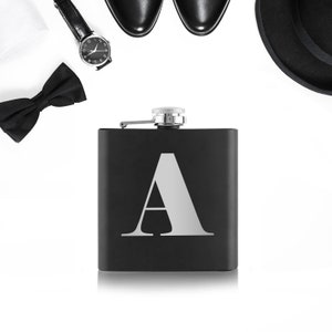 May include: A black flask with a silver cap and the letter "A" engraved on the front.