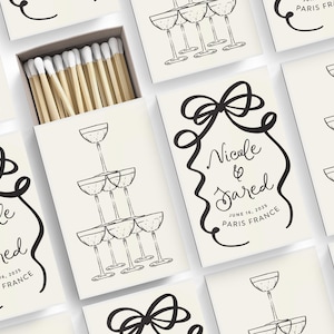May include: Wedding matchboxes with a black and white illustration of a champagne tower and the text "Nicole & Jared" with the wedding date and location.