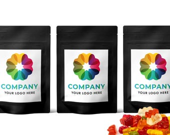 May include: Three black stand-up pouches with white labels featuring a colorful, multi-petaled flower logo above the text COMPANY YOUR LOGO HERE. A pile of assorted multicolored gummy bears sits in the foreground below the pouches.