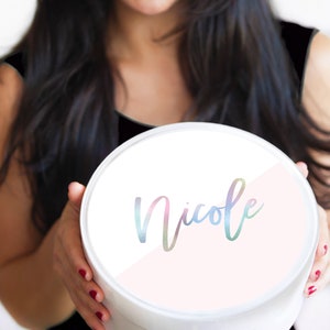 May include: A white round gift box with a pink and white design. The name "Nicole" is written in a rainbow iridescent font on the box.