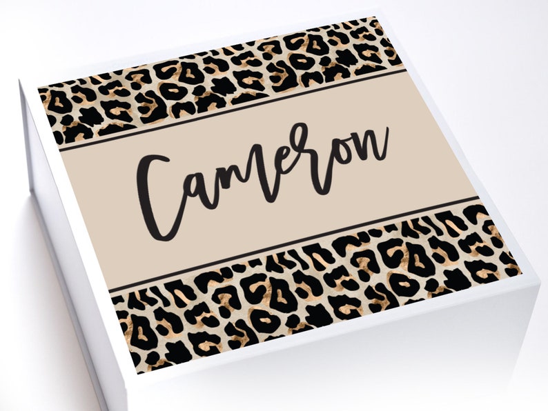 May include: A white gift box with a leopard print design and the name "Cameron" printed on the front.