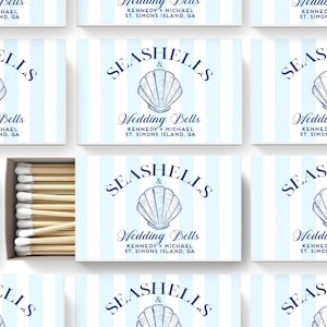 May include: A set of matchboxes with a blue and white striped background. Each box features a seashell illustration and the text "Seashells & Wedding Bells" with the couple's names and location.