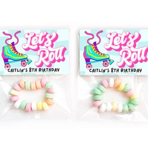 May include: Two favor bags with a blue and white checkered background. Each bag has a pink and yellow roller skate with the text "Let's Roll" and "Caitlin's 8th Birthday". Each bag contains a bracelet made of colorful candy.