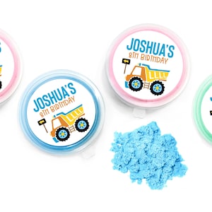 May include: Four round containers with lids, each containing blue sand. The lids have a printed design of a yellow dump truck with the text "Joshua's 8th Birthday".