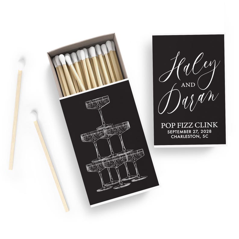 a matchbox with a stack of champagne glasses on it, along with a card that reads "Haley and Daran" and "POP PIZZ CLINK SEPTEMBER 27, 2008 CHARLESTON, SC".