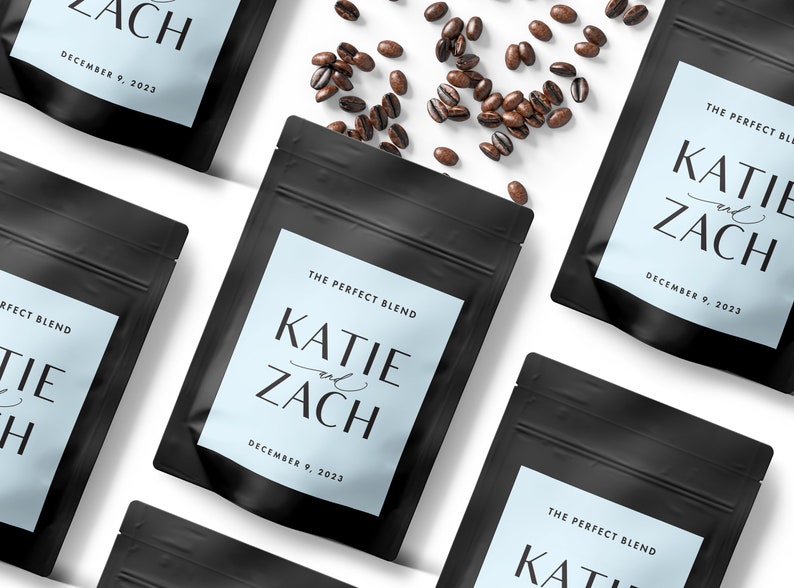 Puede incluir: Tres bolsas de caf&eacute; negras con etiquetas blancas. Las etiquetas tienen un fondo azul claro y dicen "The Perfect Blend" con los nombres "Katie y Zach" y la fecha "December 9, 2023".