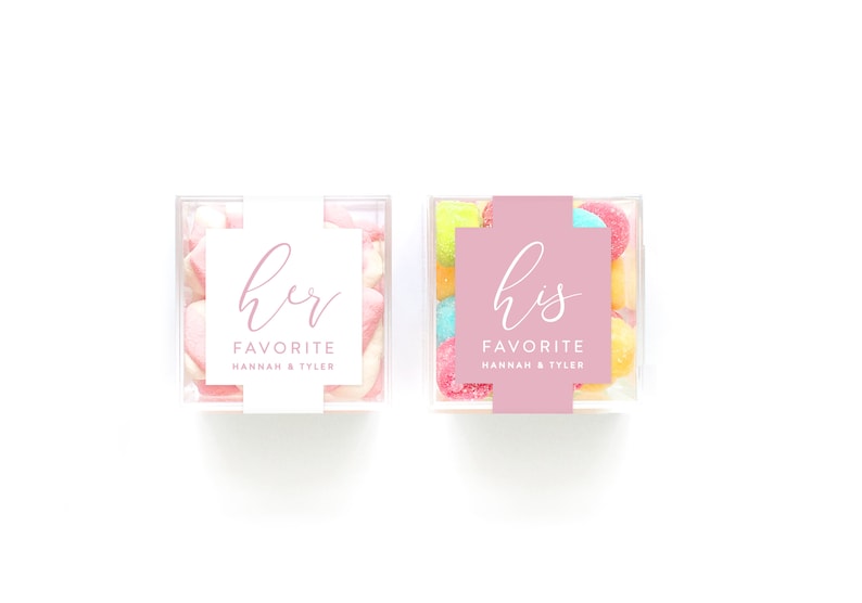 May include: Two clear plastic containers filled with candy. One container has pink and white marshmallows and a white label with the text "her favorite Hannah & Tyler". The other container has colorful candies and a pink label with the text "his favorite Hannah & Tyler".