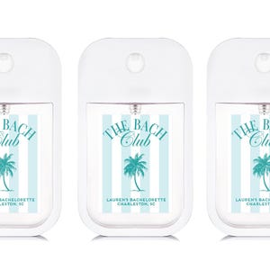 three identical white spray bottles with blue and green labels, each featuring the text "THE BACH CLUB" and "LAUREN'S BACHLONERTE CHAPELON, SC".