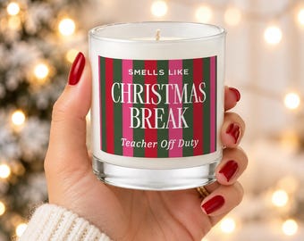 May include: A clear glass candle with a white wax fill and a single wick. The label features vertical stripes in dark green, red, and pink, with the white text: SMELLS LIKE CHRISTMAS BREAK Teacher Off Duty.