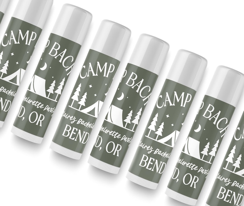 May include: A set of six green and white lip balm tubes with the text "Camp Bachelorette Party Bend, OR" printed on each tube. The tubes feature a camping tent, trees, and stars.
